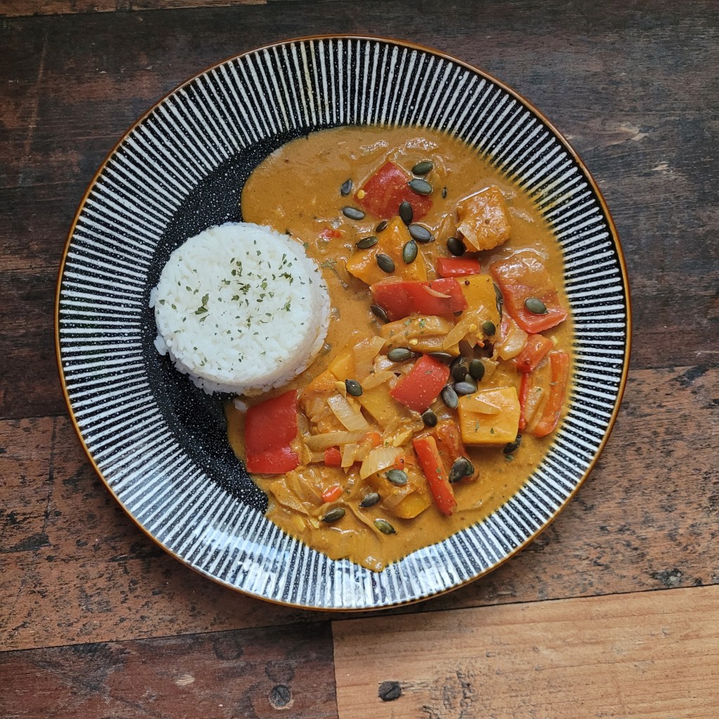 A vibrant curry with peppers and served with rice.