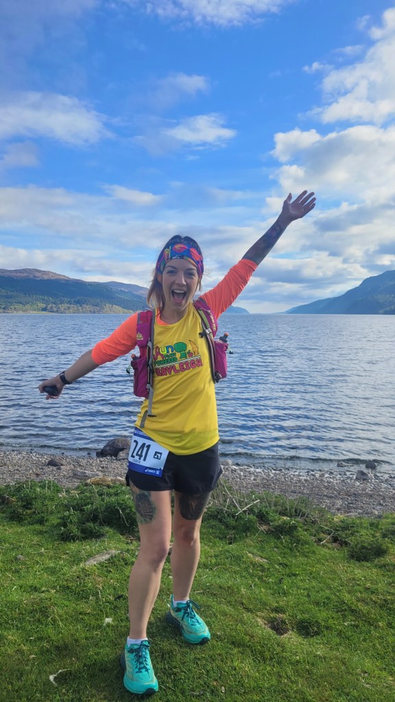 Kayleigh standing happy with arms in the air at Loch Ness